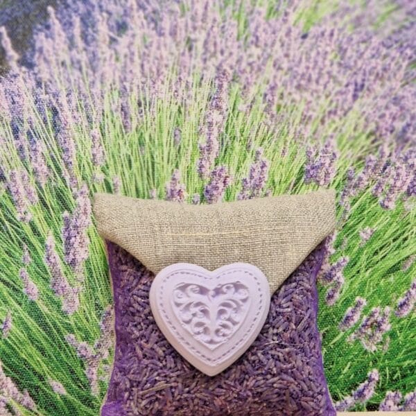 Sachet carré en lin et tulle violet garni de lavandin, orné d’un grand cœur volute en plâtre parfumable, à suspendre pour parfumer le linge.