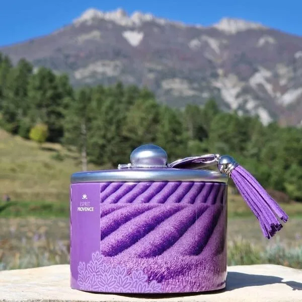 Boîte métal de bonbons à la lavande givrés, 85 g, arôme d’huile essentielle AOP, décor champs de lavande avec pompon violet, présentée sur fond neutre.