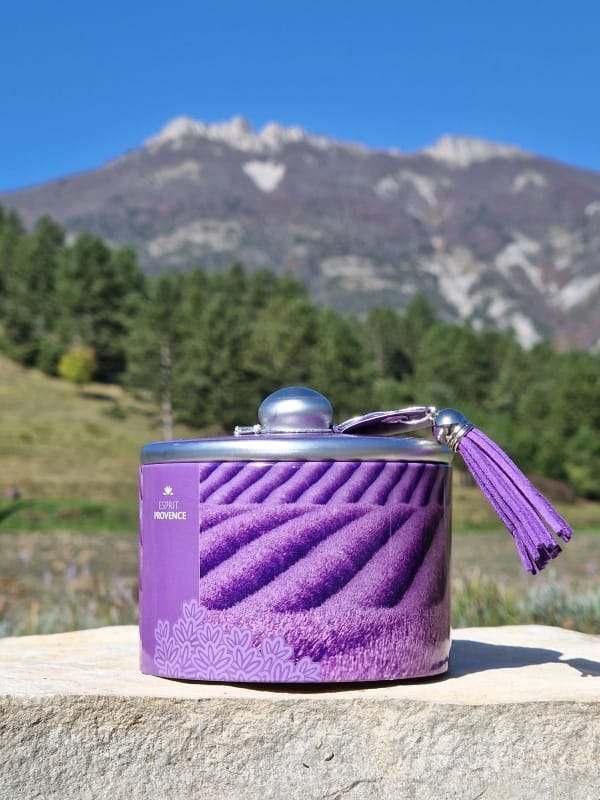 Boîte métal de bonbons à la lavande givrés, 85 g, arôme d’huile essentielle AOP, décor champs de lavande avec pompon violet, présentée sur fond neutre.