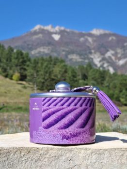 Boîte métal de bonbons à la lavande givrés, 85 g, arôme d’huile essentielle AOP, décor champs de lavande avec pompon violet, présentée sur fond neutre.