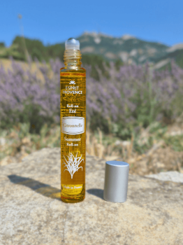 Roll-on Citronnelle de Java posé sur une pierre devant un champ de lavande